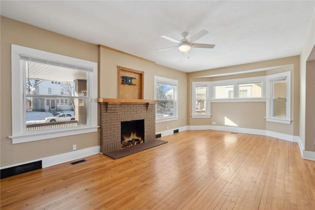 unfurnished living room featuring a brick fireplace, visible vents, and light wood-style flooring