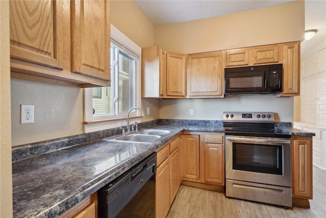 kitchen with black appliances, light wood finished floors, and a sink