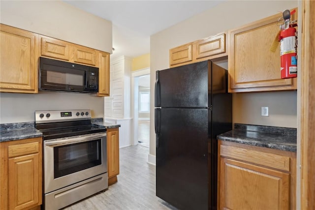 kitchen featuring dark stone counters, black appliances, and light wood-style floors