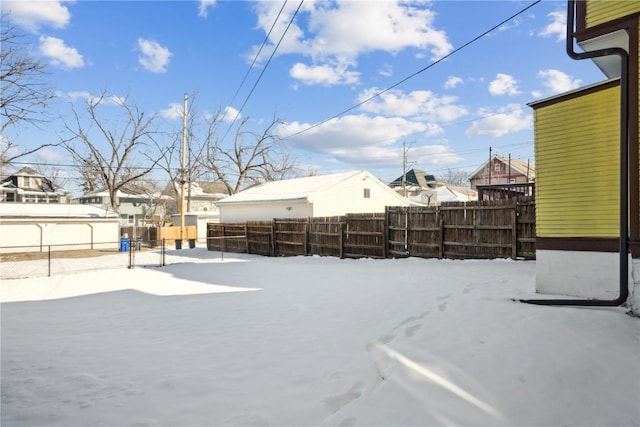 yard covered in snow with a residential view and fence