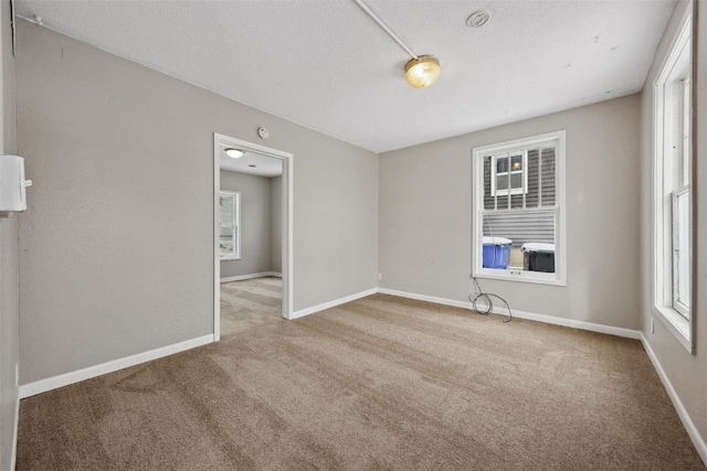 spare room with light carpet and a textured ceiling