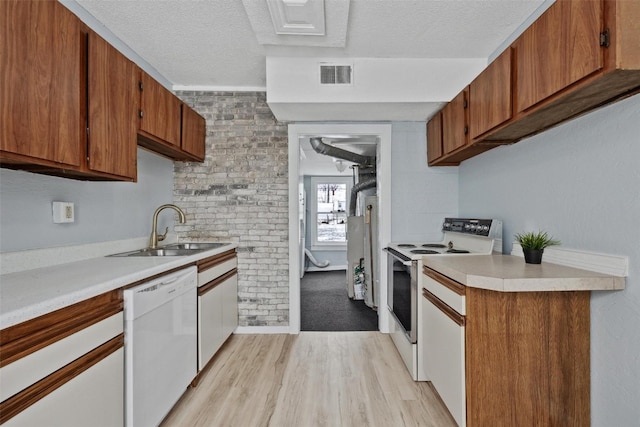 kitchen featuring a textured ceiling, light wood-type flooring, white appliances, and sink