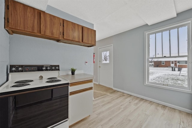 kitchen with white range with electric stovetop, plenty of natural light, light hardwood / wood-style floors, and a textured ceiling