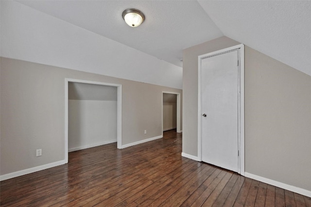 additional living space featuring dark hardwood / wood-style floors, a textured ceiling, and vaulted ceiling