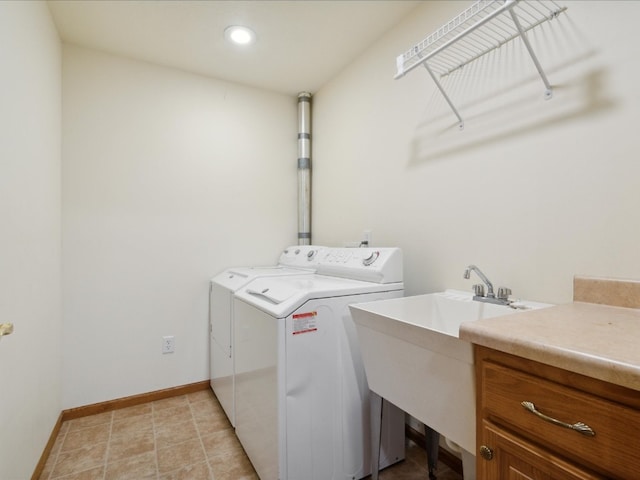 clothes washing area featuring washing machine and dryer, sink, and cabinets