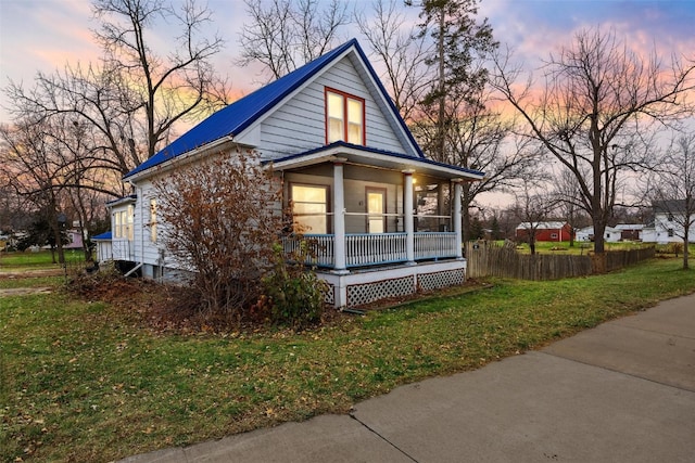 property exterior at dusk with a lawn and a porch