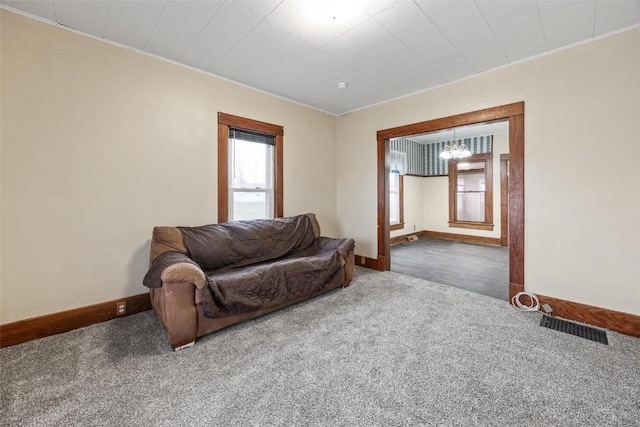 living room with carpet floors, crown molding, and a chandelier