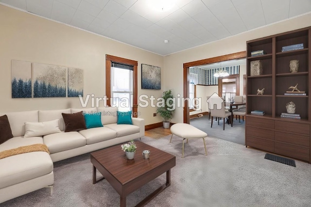 carpeted living room featuring crown molding and a notable chandelier