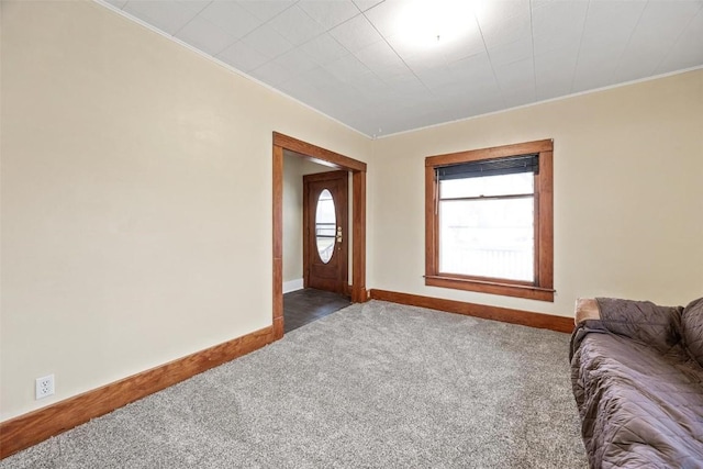 foyer with crown molding and dark carpet