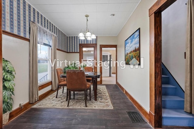 dining area with dark wood-type flooring and a notable chandelier