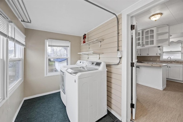 clothes washing area with light colored carpet, washer and clothes dryer, and sink