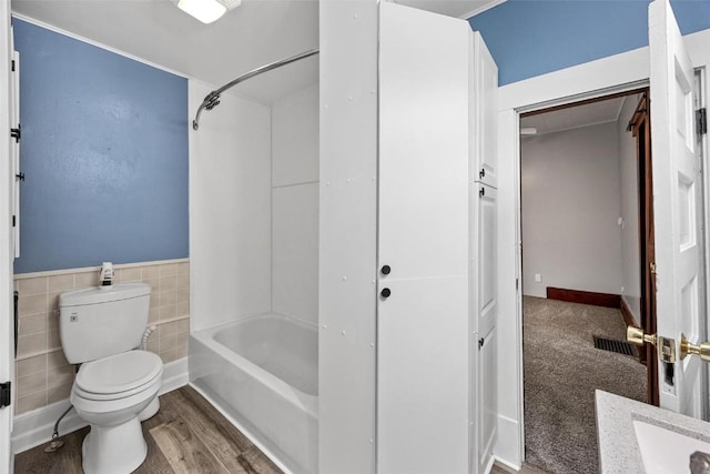 full bathroom with vanity, shower / bathing tub combination, hardwood / wood-style flooring, tile walls, and toilet