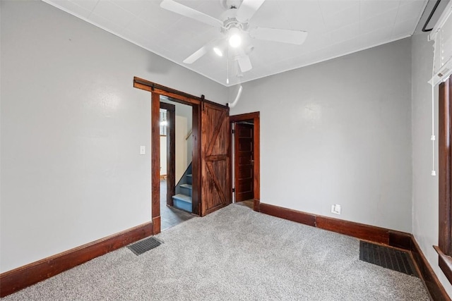 carpeted bedroom with a barn door and ceiling fan