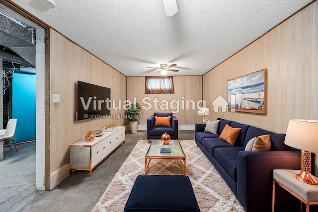 living room with ceiling fan, wood walls, and a textured ceiling