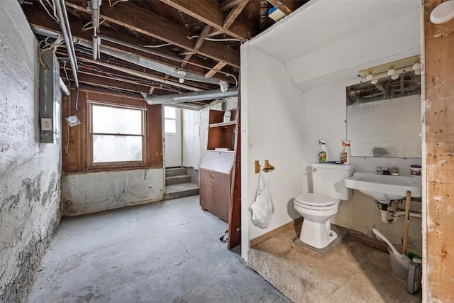 bathroom with concrete flooring, toilet, and sink