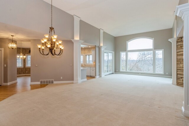 unfurnished living room with ornate columns, light carpet, and a healthy amount of sunlight