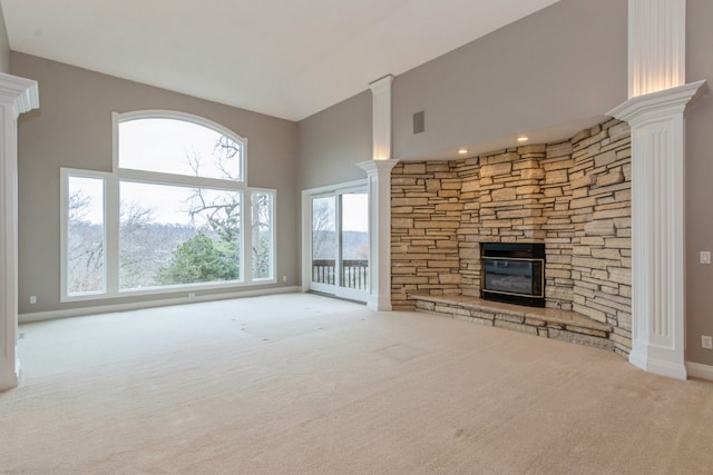 unfurnished living room with a fireplace, light colored carpet, plenty of natural light, and decorative columns