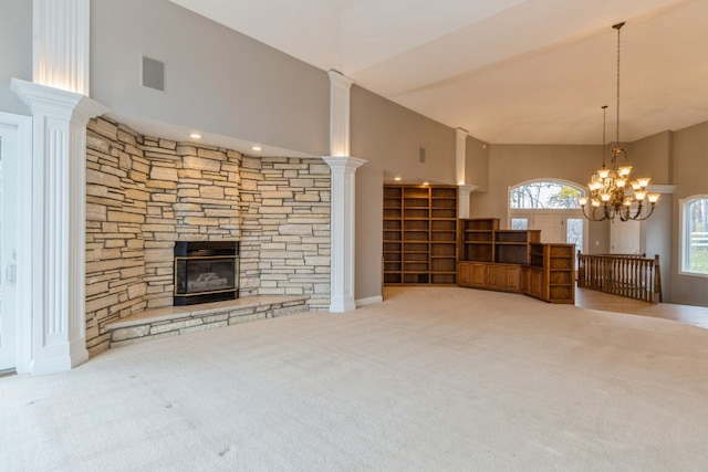 unfurnished living room featuring ornate columns, a stone fireplace, high vaulted ceiling, a notable chandelier, and light colored carpet