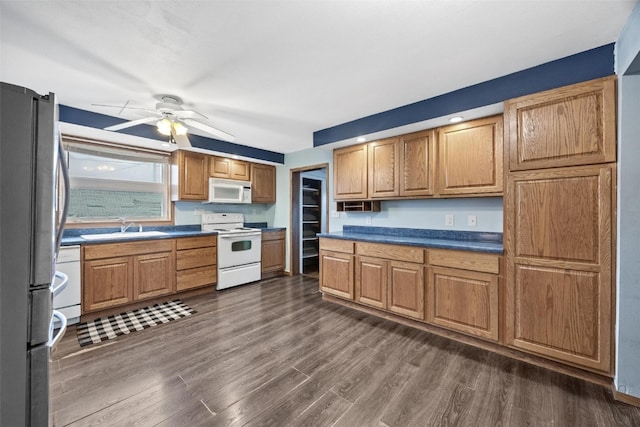 kitchen with ceiling fan, sink, dark wood-type flooring, and white appliances