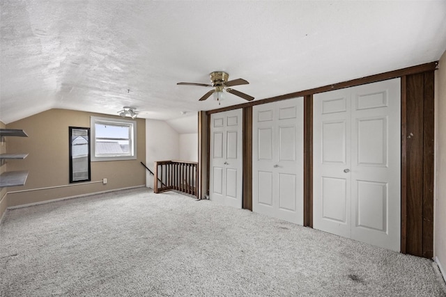 unfurnished bedroom featuring a textured ceiling, carpet floors, ceiling fan, and lofted ceiling