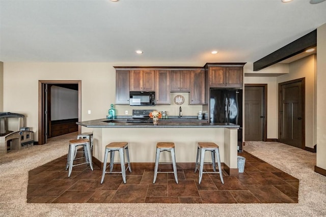 kitchen featuring dark colored carpet, a kitchen breakfast bar, and black appliances