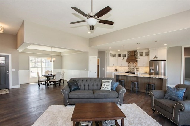 living room with ceiling fan with notable chandelier and dark wood-type flooring