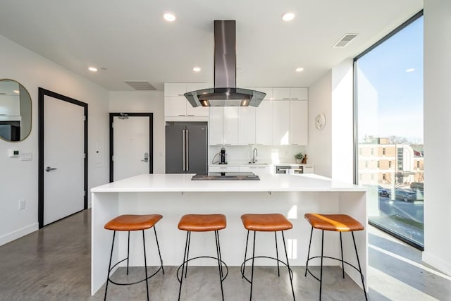 kitchen featuring white cabinetry, sink, a kitchen bar, island range hood, and high end fridge