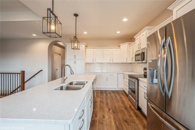 kitchen featuring sink, stainless steel appliances, an island with sink, pendant lighting, and white cabinets