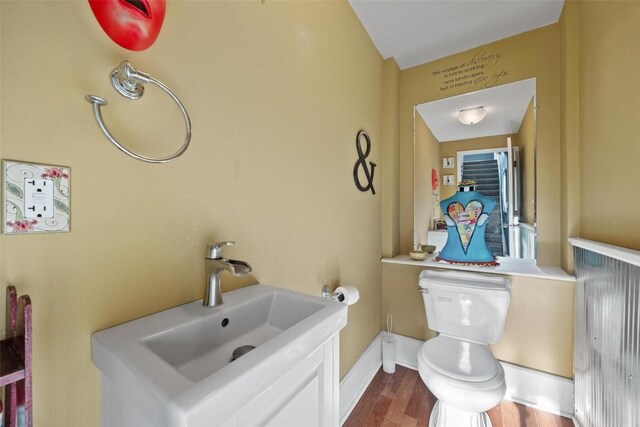 bathroom with toilet, sink, and hardwood / wood-style flooring