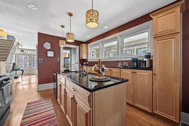 kitchen featuring light wood-type flooring, black electric range oven, sink, pendant lighting, and a kitchen island