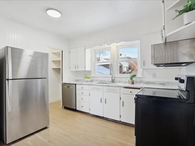 kitchen featuring appliances with stainless steel finishes, light hardwood / wood-style flooring, white cabinetry, and sink