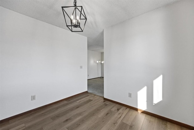 unfurnished dining area featuring dark hardwood / wood-style flooring, a textured ceiling, and a chandelier