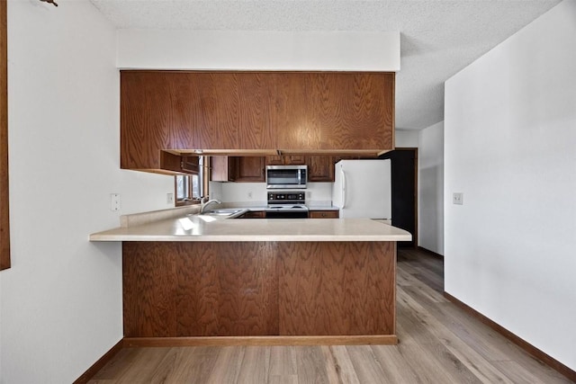 kitchen featuring light hardwood / wood-style floors, black range, white fridge, and kitchen peninsula