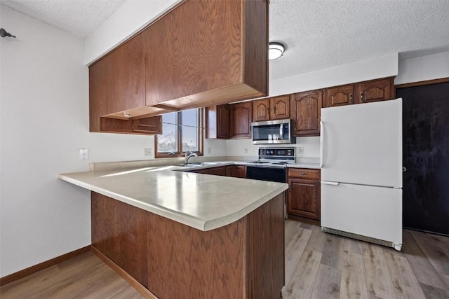 kitchen featuring white refrigerator, range with electric cooktop, light wood-type flooring, a textured ceiling, and kitchen peninsula