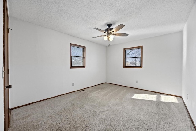 spare room with light carpet, a textured ceiling, a wealth of natural light, and ceiling fan