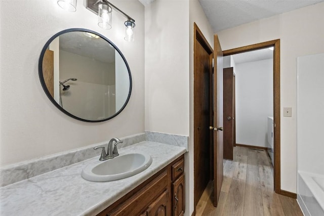 bathroom featuring a shower, hardwood / wood-style floors, vanity, and a textured ceiling