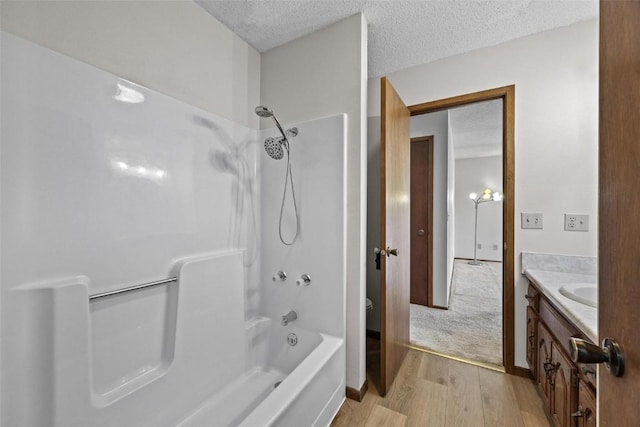 bathroom featuring hardwood / wood-style flooring, vanity, shower / bathing tub combination, and a textured ceiling