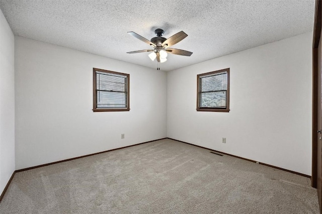 empty room featuring ceiling fan, a textured ceiling, and light carpet