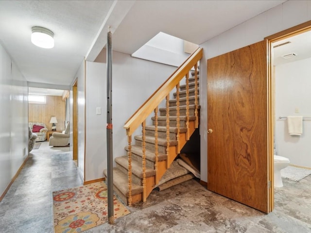 stairway featuring wooden walls