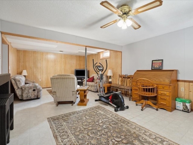 workout room with wooden walls, ceiling fan, and a textured ceiling