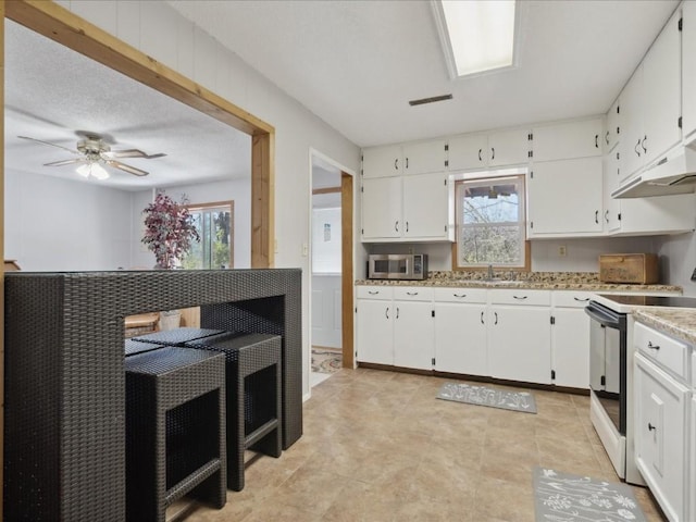 kitchen with a textured ceiling, ceiling fan, sink, electric stove, and white cabinetry