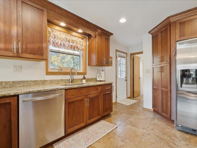 kitchen with light stone counters, sink, and appliances with stainless steel finishes