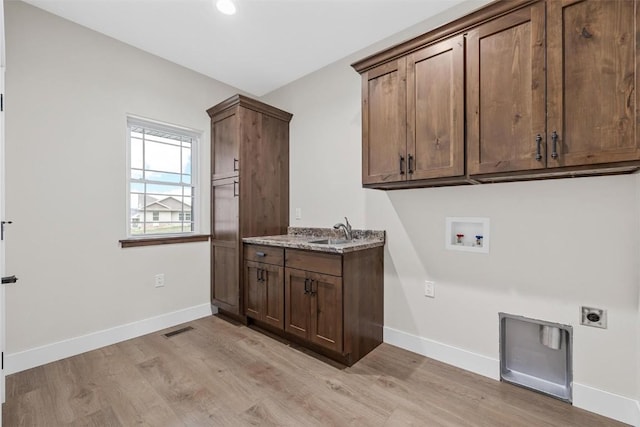 clothes washing area with sink, washer hookup, cabinets, hookup for an electric dryer, and light wood-type flooring