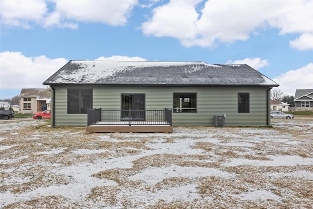 snow covered back of property with central AC unit and a wooden deck