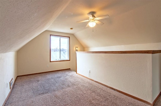 additional living space featuring vaulted ceiling, a textured ceiling, ceiling fan, and carpet flooring