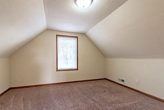 bonus room with lofted ceiling, a textured ceiling, and carpet