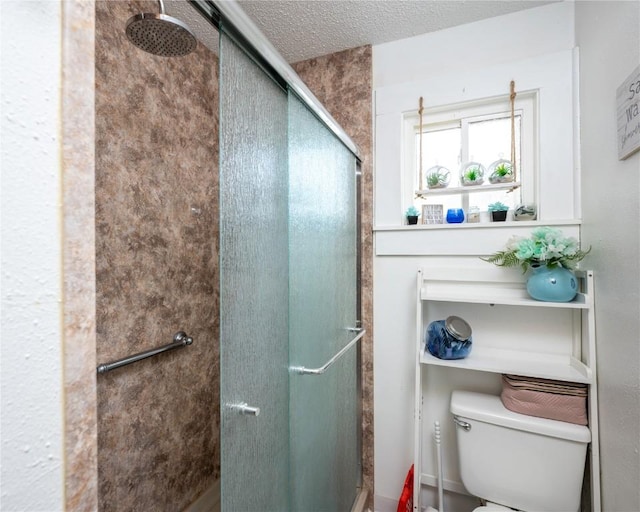 bathroom with toilet, a shower with door, and a textured ceiling