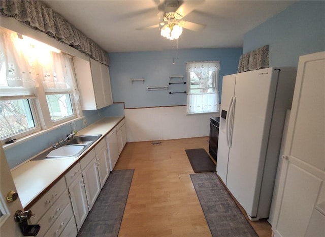 kitchen with white cabinetry, sink, white fridge with ice dispenser, ceiling fan, and light hardwood / wood-style flooring