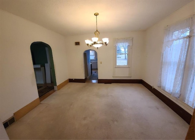 spare room with a chandelier and carpet