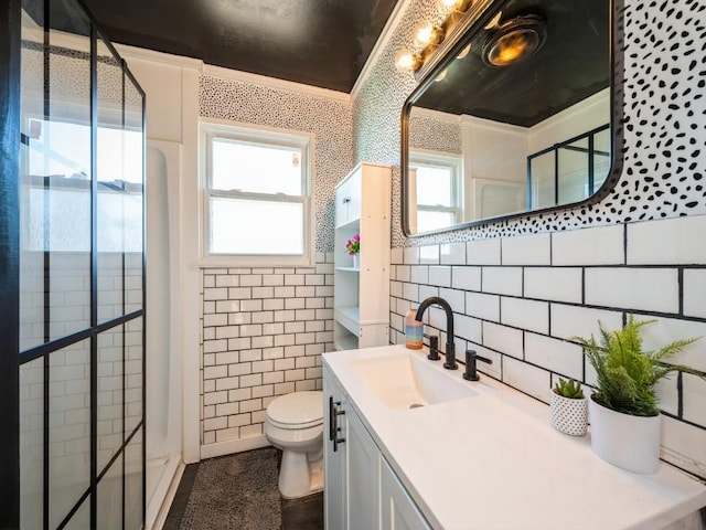 bathroom with vanity, crown molding, toilet, tile walls, and a tile shower